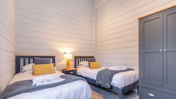 Une chambre avec deux lits, des tables de chevet, des lampes et une armoire.