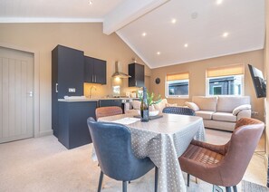 A modern kitchen with dark cabinets, a dining table with a polka dot tablecloth, and a sofa in the living area.