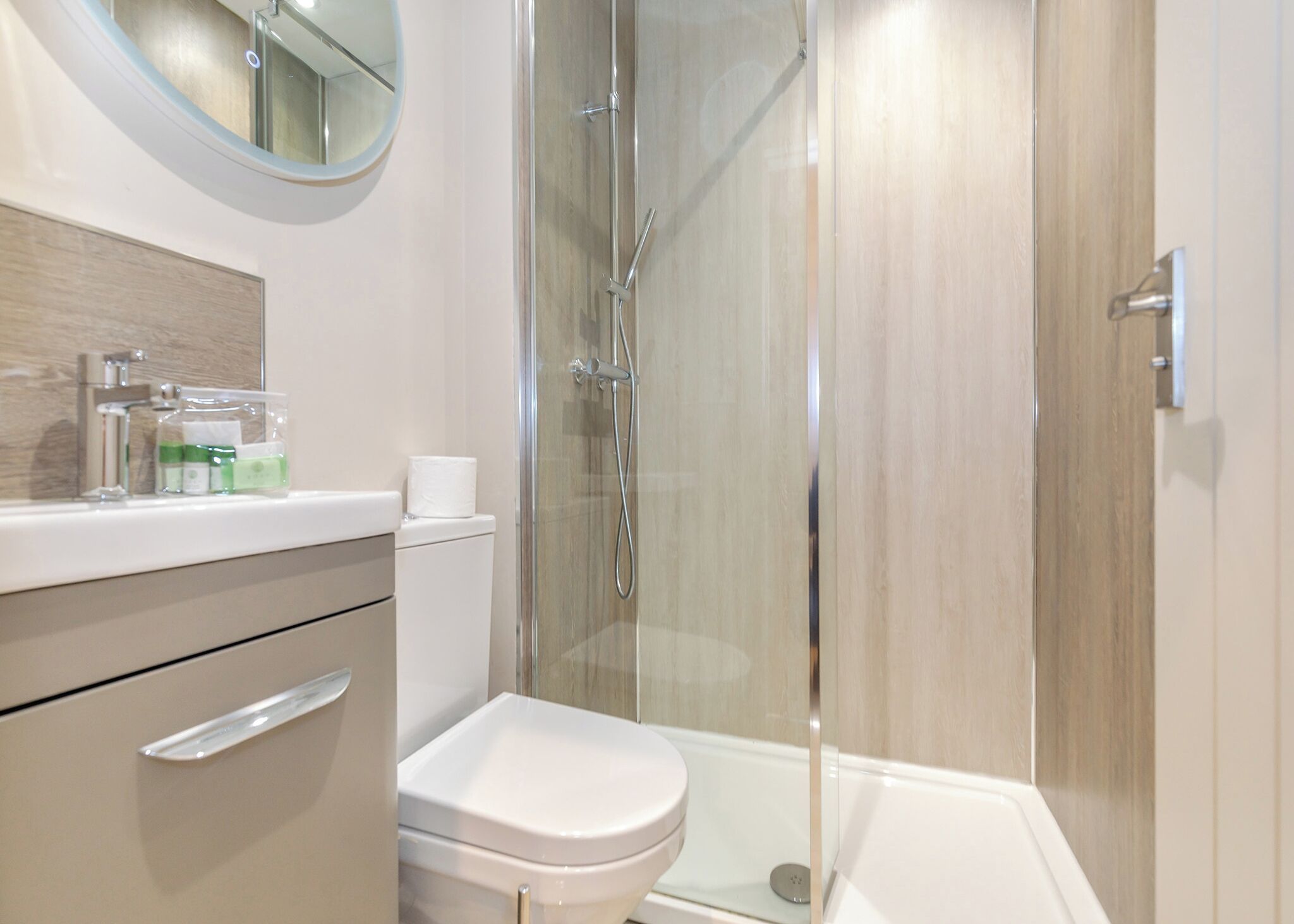 Een moderne badkamer met een douchecabine van glas, een toilet en een wastafel met spiegel.