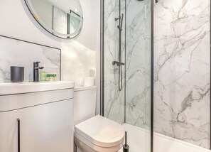 Ein Badezimmer mit Toilette, Waschbecken, Spiegel und Dusche.