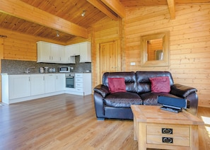 A log cabin interior with a kitchen, a leather sofa, and a wooden coffee table. - Luxurious solid log lodge. (Wenhaston, Halesworth)
