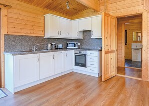 A modern kitchen with white cabinets, granite countertops, and stainless steel appliances. - Luxurious solid log lodge. (Wenhaston, Halesworth)