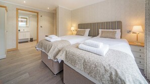 Un letto matrimoniale con due cuscini, un comodino con una lampada e uno specchio con luci sopra.