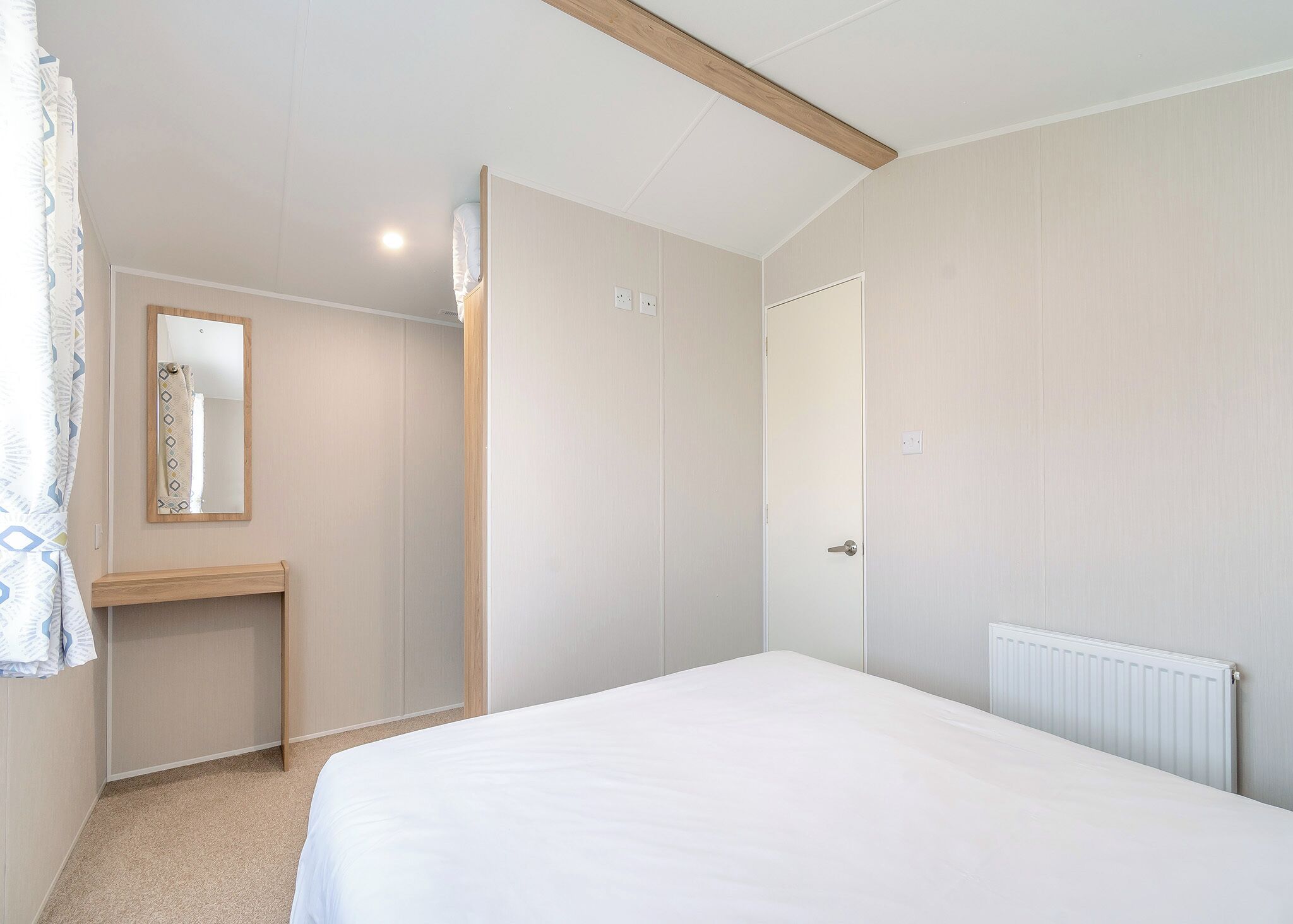 Une chambre à coucher avec un lit, une table de chevet, un miroir, une porte et un radiateur.