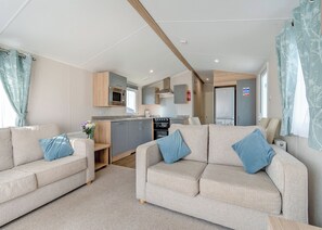 A modern RV interior with two sofas, a kitchenette, and a dining area.