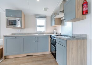 A modern kitchen with grey cabinets, a stainless steel oven, a built-in microwave, and a gas stove.