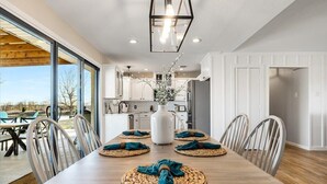 Una cocina moderna con armarios blancos, una isla grande y una zona de comedor con una mesa y sillas de madera.