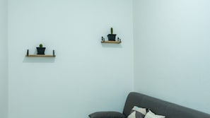 A room with a grey sofa and two wall-mounted shelves with potted plants. - Casa Pico - Centrally located with parking Wi-Fi (Mirandola)
