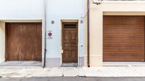 Um edifício com uma porta de madeira fechada, placa de proibido estacionar e um número na porta.