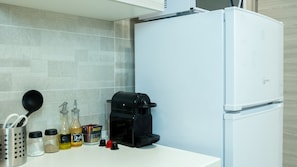 Uma cozinha com geladeira branca, cafeteira e diversos utensílios e recipientes.