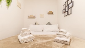 A hotel room with a bed, white towels, a small table, and a wall-mounted shelf. - Casa Pico - Centrally located with parking Wi-Fi (Mirandola)