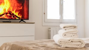 A neatly made bed with a folded towel and a television displaying a fire. - Casa Pico - Centrally located with parking Wi-Fi (Mirandola)