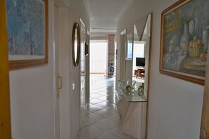 A hallway with white walls, a tiled floor, and a glass display case with decorative items.