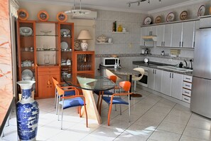 Eine moderne Küche mit Essbereich, ausgestattet mit einem runden Glastisch, orangefarbenen Stühlen und einer großen, blauen Vase.