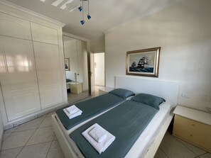 Ein Schlafzimmer mit zwei Betten, einem Kleiderschrank, einem Nachttisch und einem Bild an der Wand.