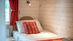 Ein Einzelbett mit Kopfteil, Nachttisch und einem Vorhangfenster.