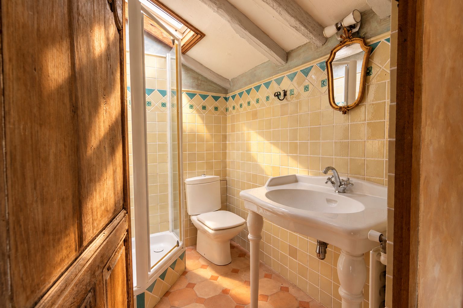 A bathroom with a toilet, sink, and a mirror on the wall.