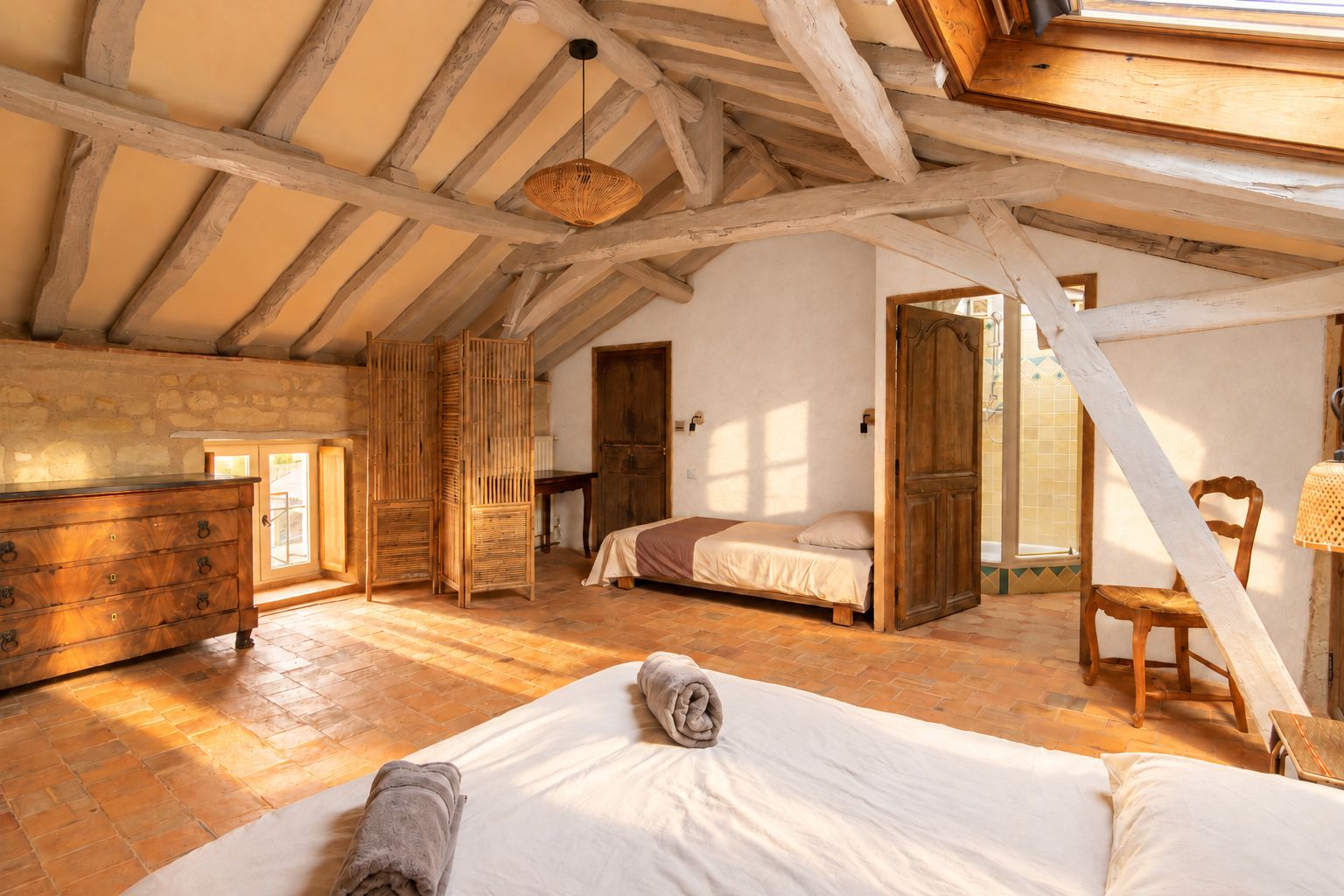 Une chambre avec un plafond en bois, un lit, une commode et une fenêtre.