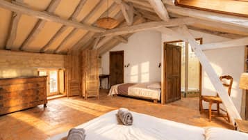 Une chambre avec un plafond en bois, un lit, une commode et une fenêtre.