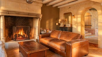 Un salon chaleureux avec une cheminée, un canapé en cuir et une table basse en bois.