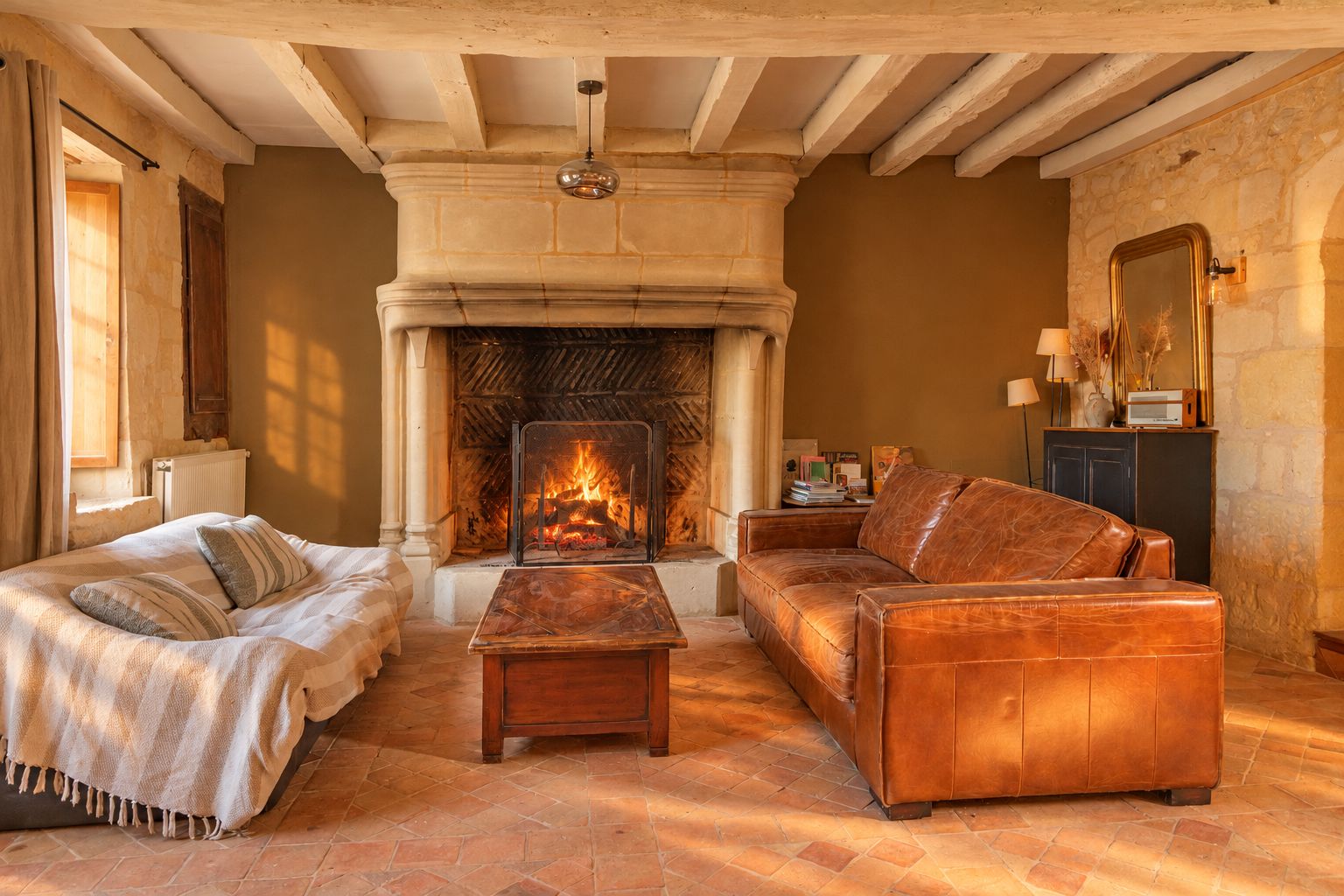 A cozy living room with a fireplace, a sofa, a coffee table, and a bed with a blanket.