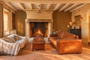 Una sala de estar acogedora con chimenea, un sofá, una mesita de centro y una cama con manta.