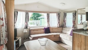 A caravan interior with a sofa, a table, and a mirror.