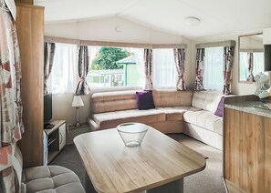 L'intérieur d'une caravane, avec un canapé, une table et un miroir.