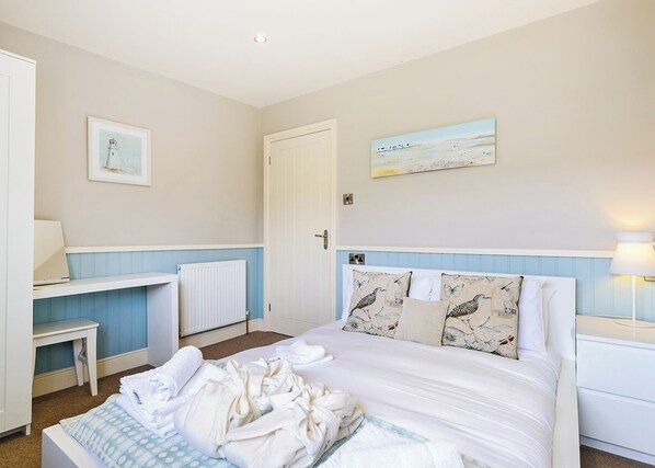 Une chambre à coucher avec un lit, un bureau, une chaise, un radiateur et une porte.