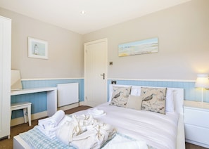 Quarto com cama, escrivaninha, cadeira, radiador e porta.