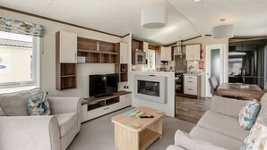 A modern living room with a flat-screen TV, sofa, coffee table, and a fireplace.