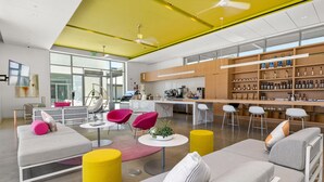 Un moderno espacio lounge con sofás, sillas y una barra con estantes llenos de botellas.