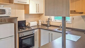 Una cocina compacta equipada con microondas, tostadora, hervidor, pileta y cocina.