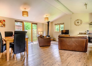 A spacious living area with a wooden floor, a sofa, a TV, and a fireplace.