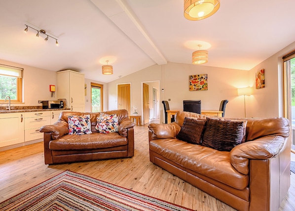 A spacious living room with leather sofas, a kitchen area, and a dining table.