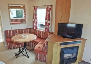 A cozy room with a sofa, a small table, a television, and a window with curtains. - Excellent Value for money Bronze range, with one double bedroom and one twin. (Clarach Bay, Nr Aberystwyth)
