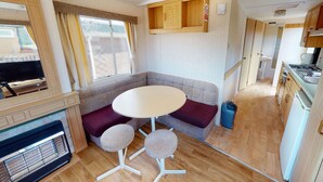 A compact RV interior with a kitchenette, a seating area with a table and chairs, and a television. - Excellent Value for money Bronze range, with one double bedroom and one twin. (Clarach Bay, Nr Aberystwyth)