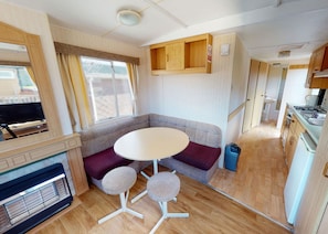 Un intérieur de camping-car compact comprenant un coin cuisine, un espace salon avec une table et des chaises, et un téléviseur.