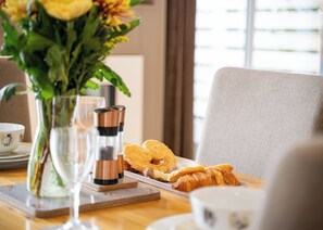 A breakfast setting with a plate of croissants, a glass of water, and a vase of flowers.