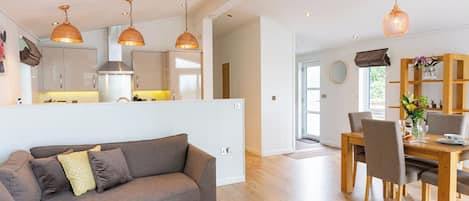 A modern living space with a sofa, dining table, and kitchen area.