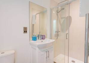 A bathroom with a glass-enclosed shower, a white sink, and a mirror above it.
