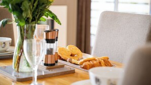 En frukostuppdukning med en tallrik full av croissanter, ett glas vatten och en vas med blommor.