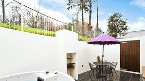 A hot tub, patio table, chairs, and a purple umbrella in a backyard setting. - Apple Cottage is a firm favourite with our guests. (Watergate, Looe)