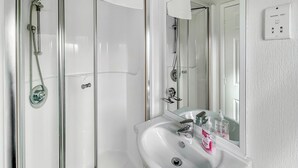 A bathroom with a glass shower enclosure, a white sink with a mirror, and a 'Shavers Only' sign. - Country Lodge Four Spa (Tintagel)