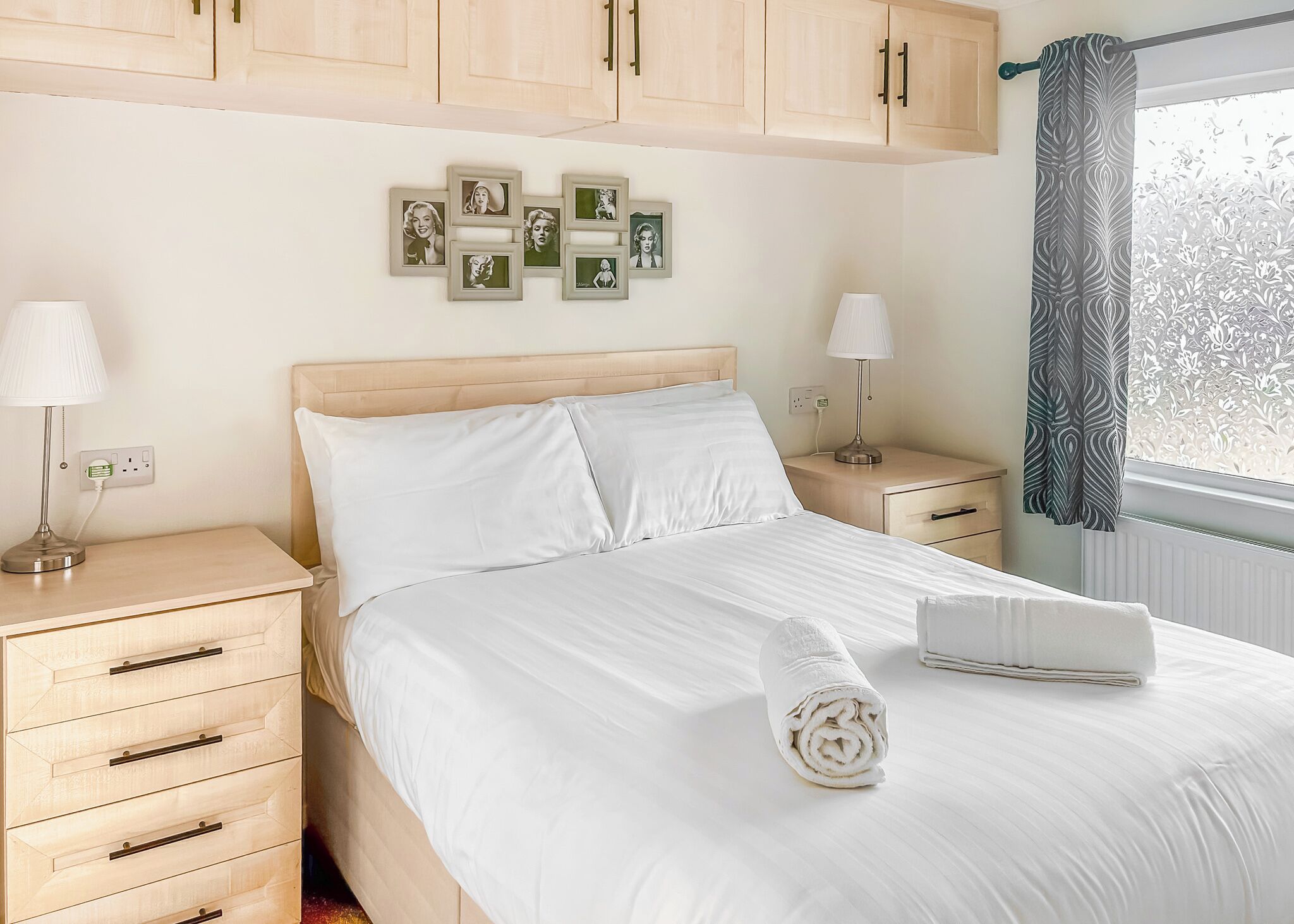 A neatly made bed with white linens, a headboard, and a bedside table with a lamp.