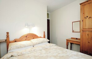 A bedroom with a wooden bed, two bedside lamps, a wooden dresser, and a mirror.