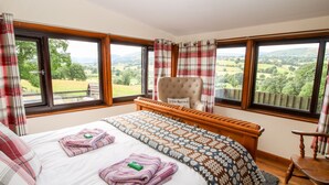 A bedroom with a large bed, a chair, and a view of the countryside. - The Retreat (Oswestry)