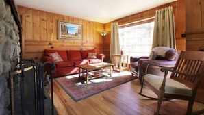 Ein gemütliches Wohnzimmer mit Holzwänden, einem roten Sofa, einem Holztisch und einem Holzstuhl.