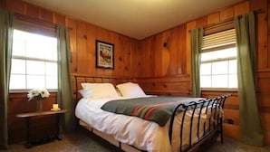 Ein Schlafzimmer mit Holzwänden, einem Bett, einem Nachttisch und einem gerahmten Bild an der Wand.
