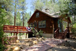 Eine rustikale Blockhütte mit Veranda, umgeben von einem Wald.